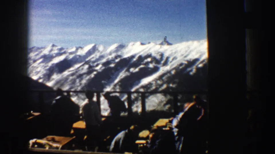 Final frame shows silhouetted lodge guests and tables in the foreground, with a clear 1961 Aspen mountain panorama outside.