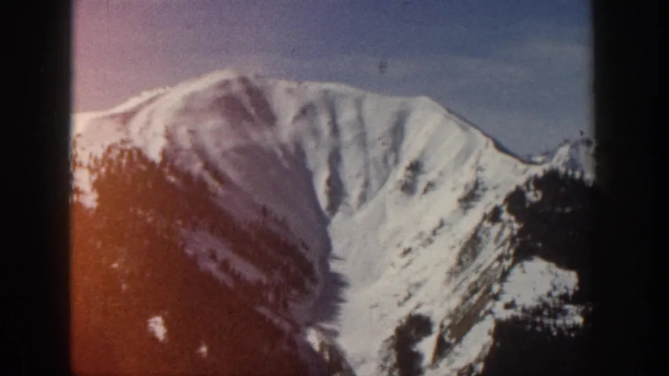 Snow-covered mountain peak near Aspen, Colorado, seen in 1961 8mm home-movie footage with soft focus and visible film edges.