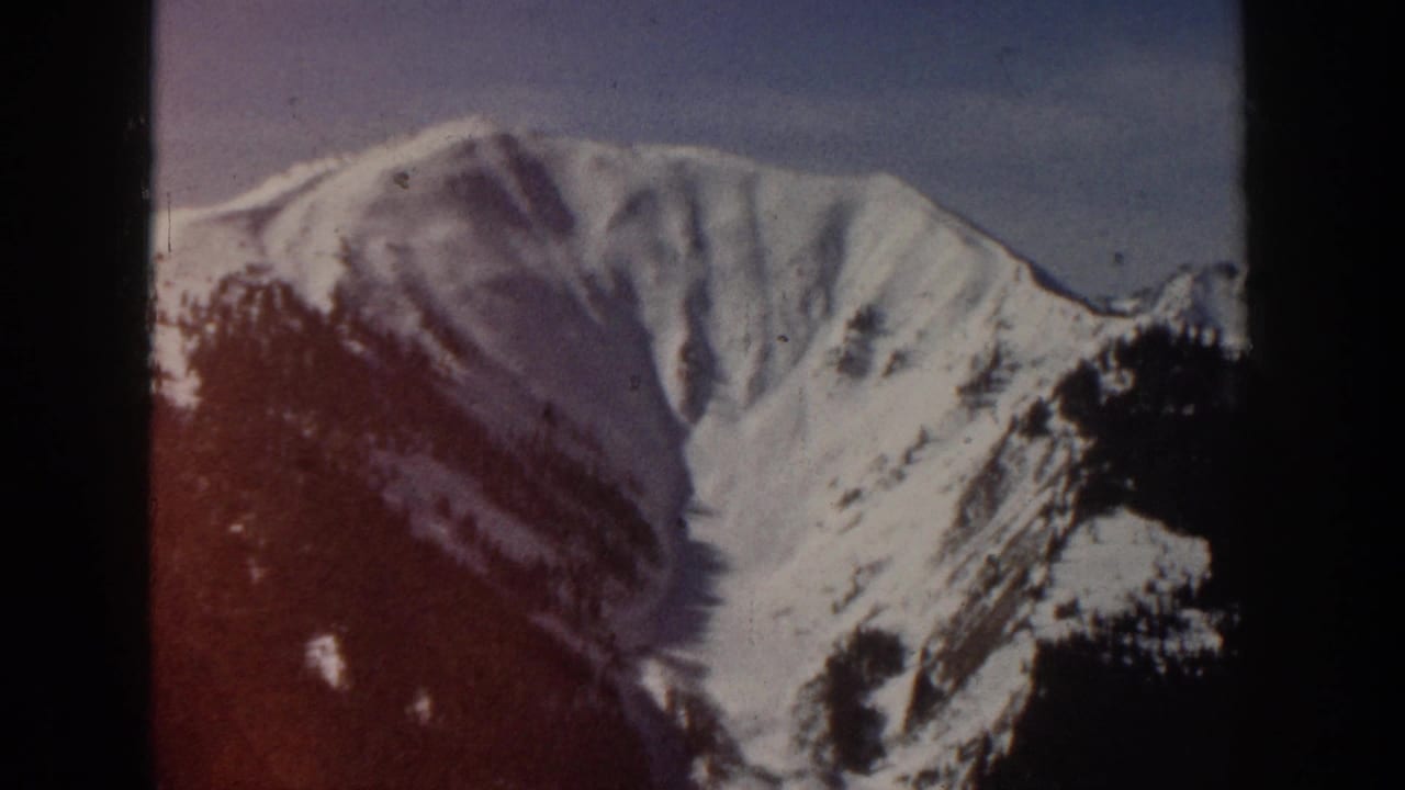 A prominent snow-covered Aspen-area mountain peak appears in soft 8mm color with visible gate edges and light film wear.