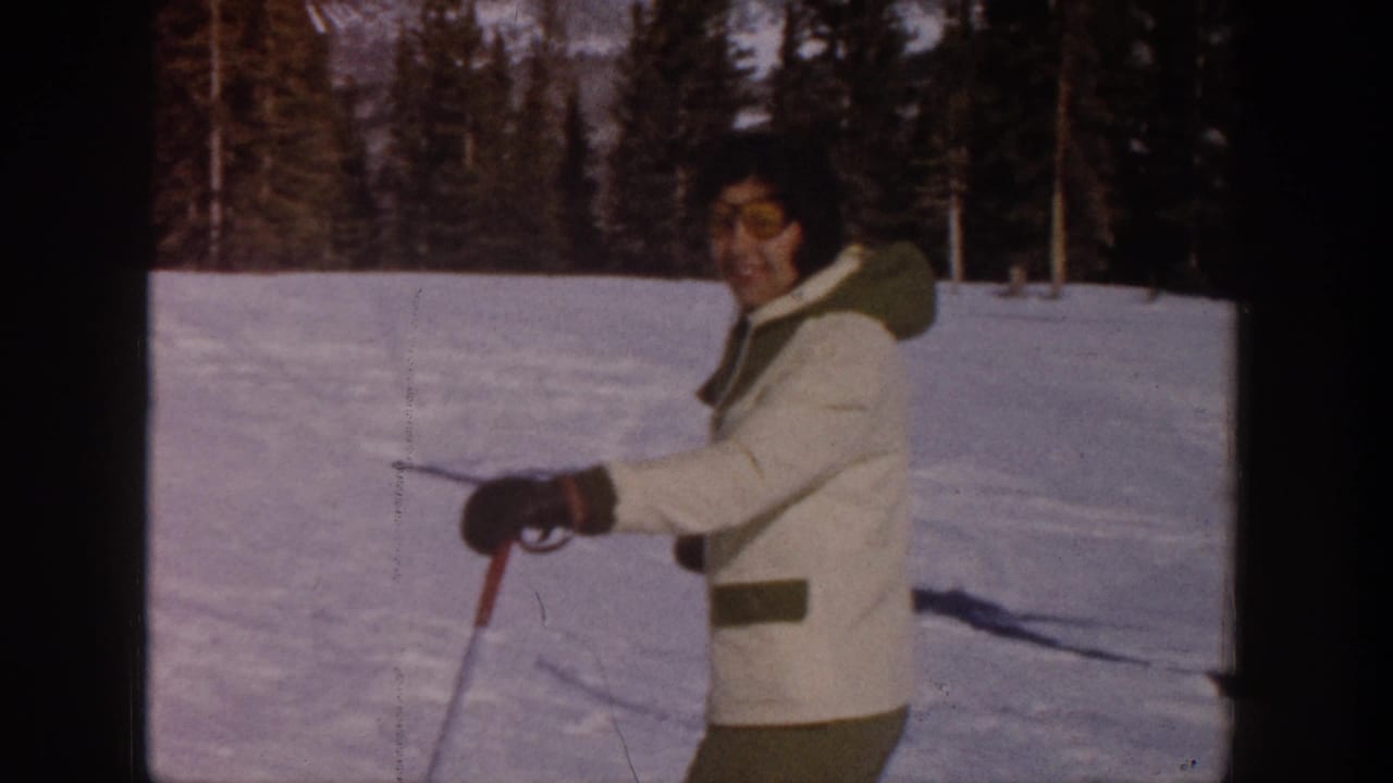 Woman in a white winter coat holding ski poles on a snowy slope.