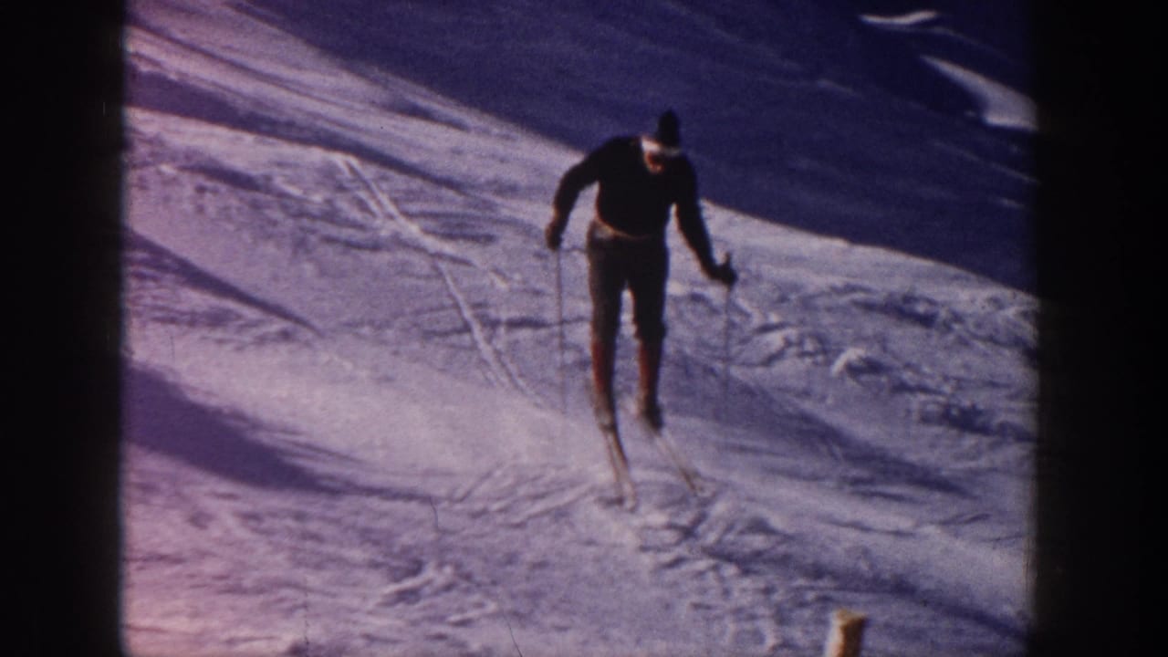 Male skier descending a snowy slope with ski poles and tracks visible.