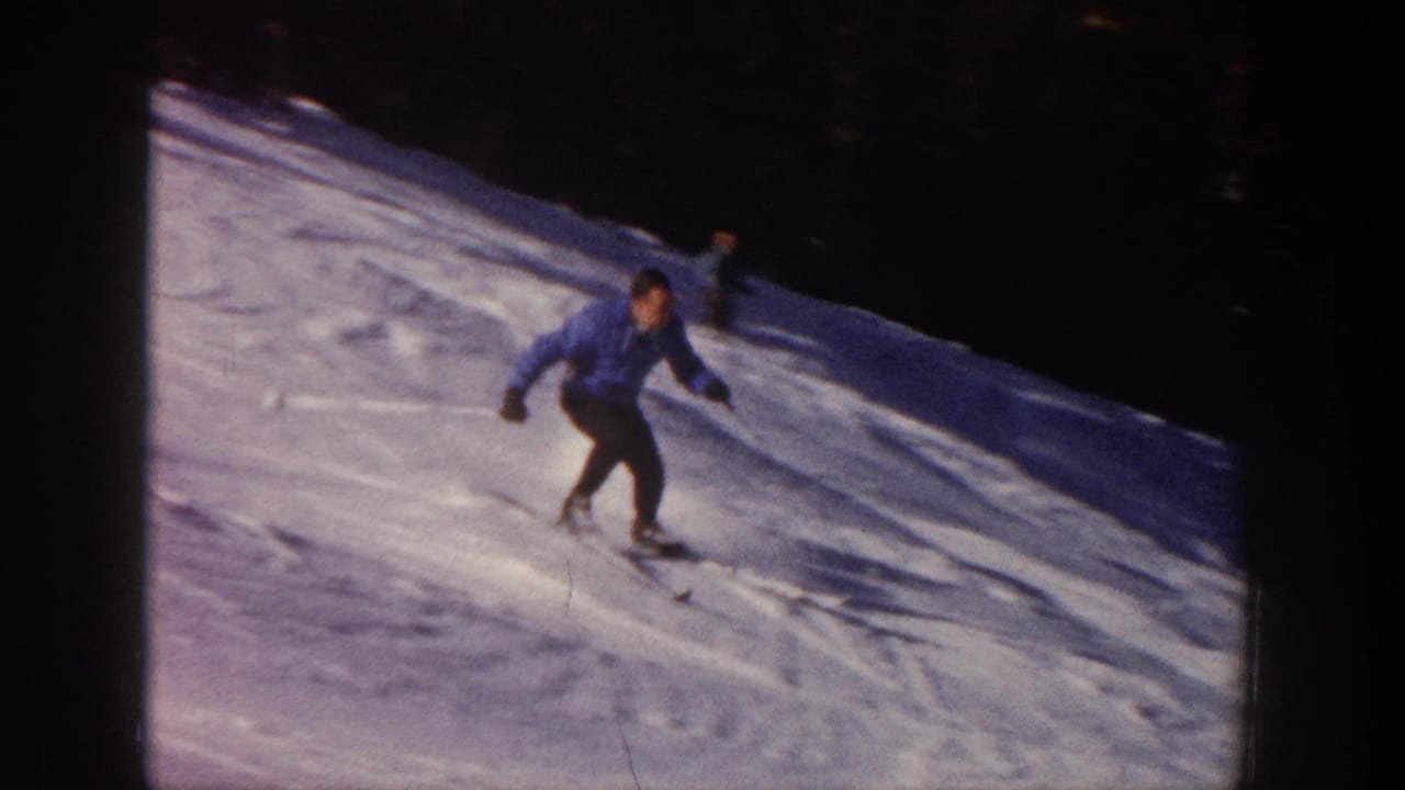 Adult skier in a blue jacket and dark pants moves downhill on a snowy Aspen slope in 1961 home-movie footage.