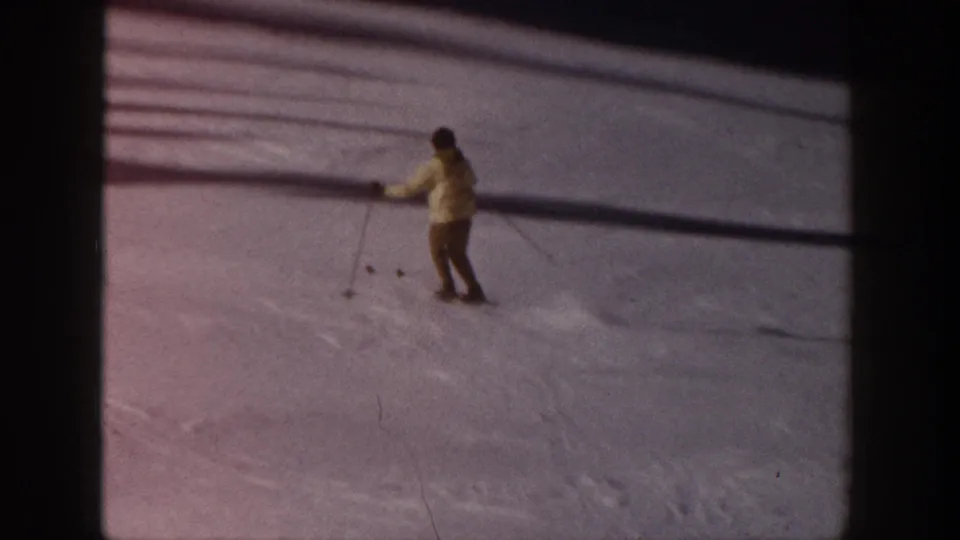 A skier in a pale jacket traverses the Aspen snowfield in a faded 1961 8mm home-movie frame.