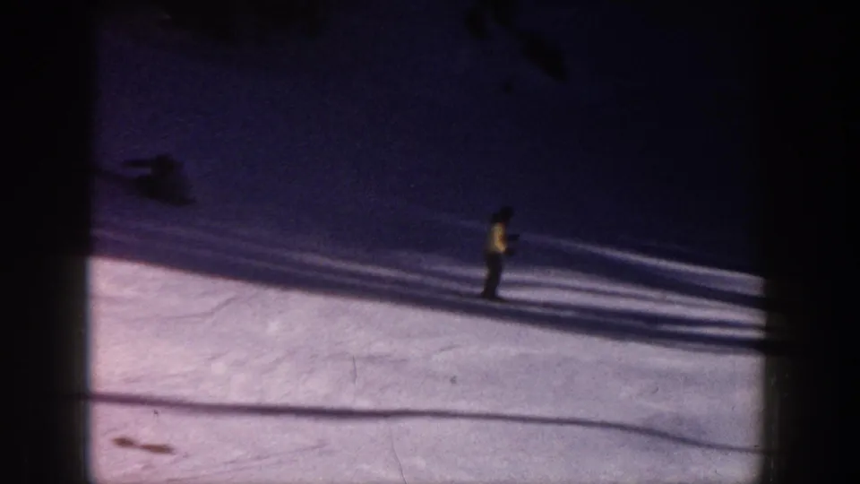 1961 Aspen frame showing a skier in a yellow coat on smooth snow, with strong shadows and dark 8mm border areas.