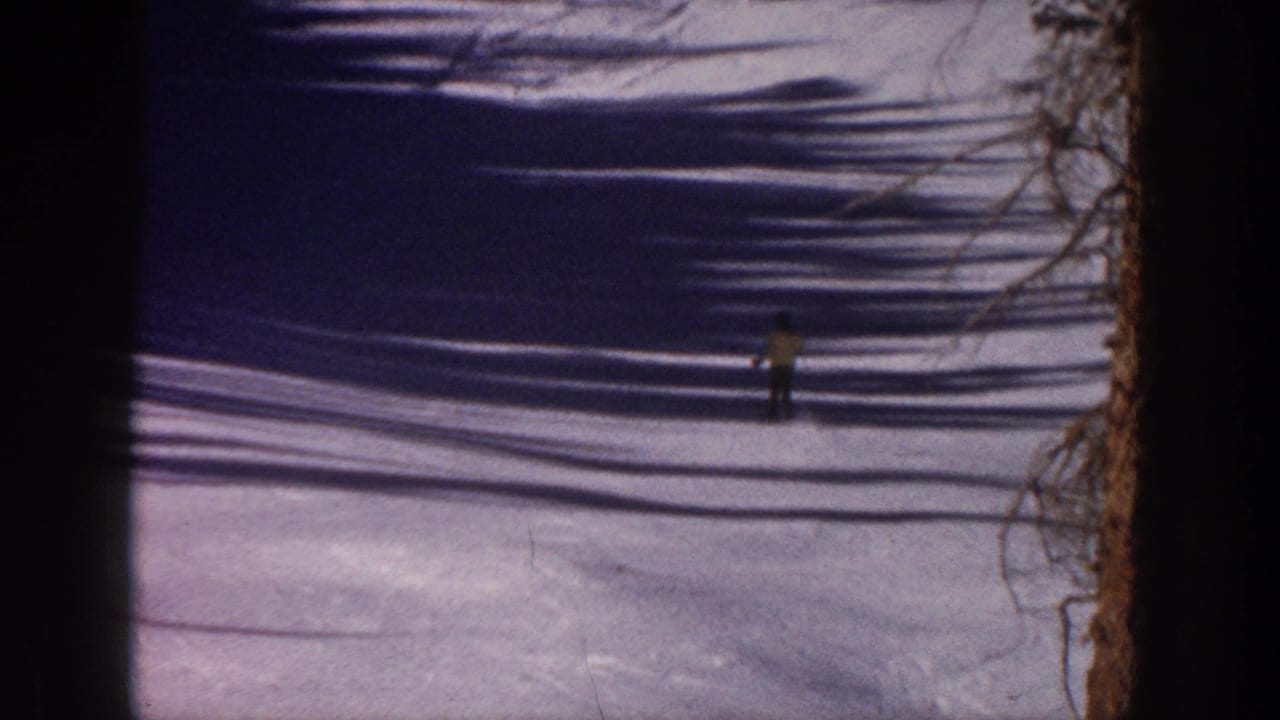 Distant skier on an Aspen snowy slope, with bare tree shadows stretching across the 1961 8mm frame.