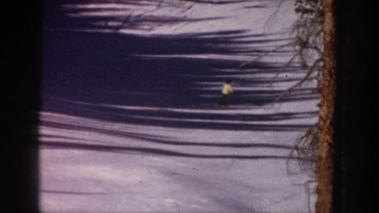 Small skier in a yellow jacket crossing a shadowed snowfield.