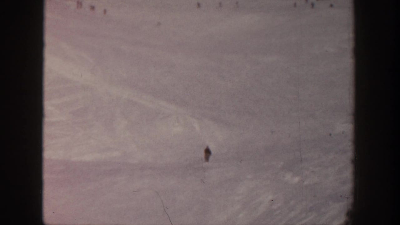1961 Aspen home-movie view of a broad snow-covered ski slope with distant skiers scattered across the hill.