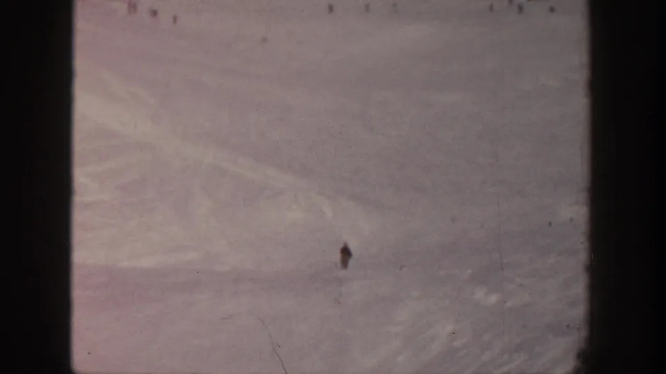 1961 Aspen home-movie view of a broad snow-covered ski slope with distant skiers scattered across the hill.