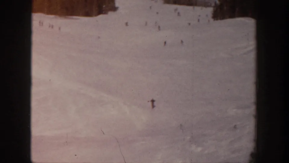 Aspen ski-slope view with one more visible skier lower in frame and other distant skiers above on the snow.