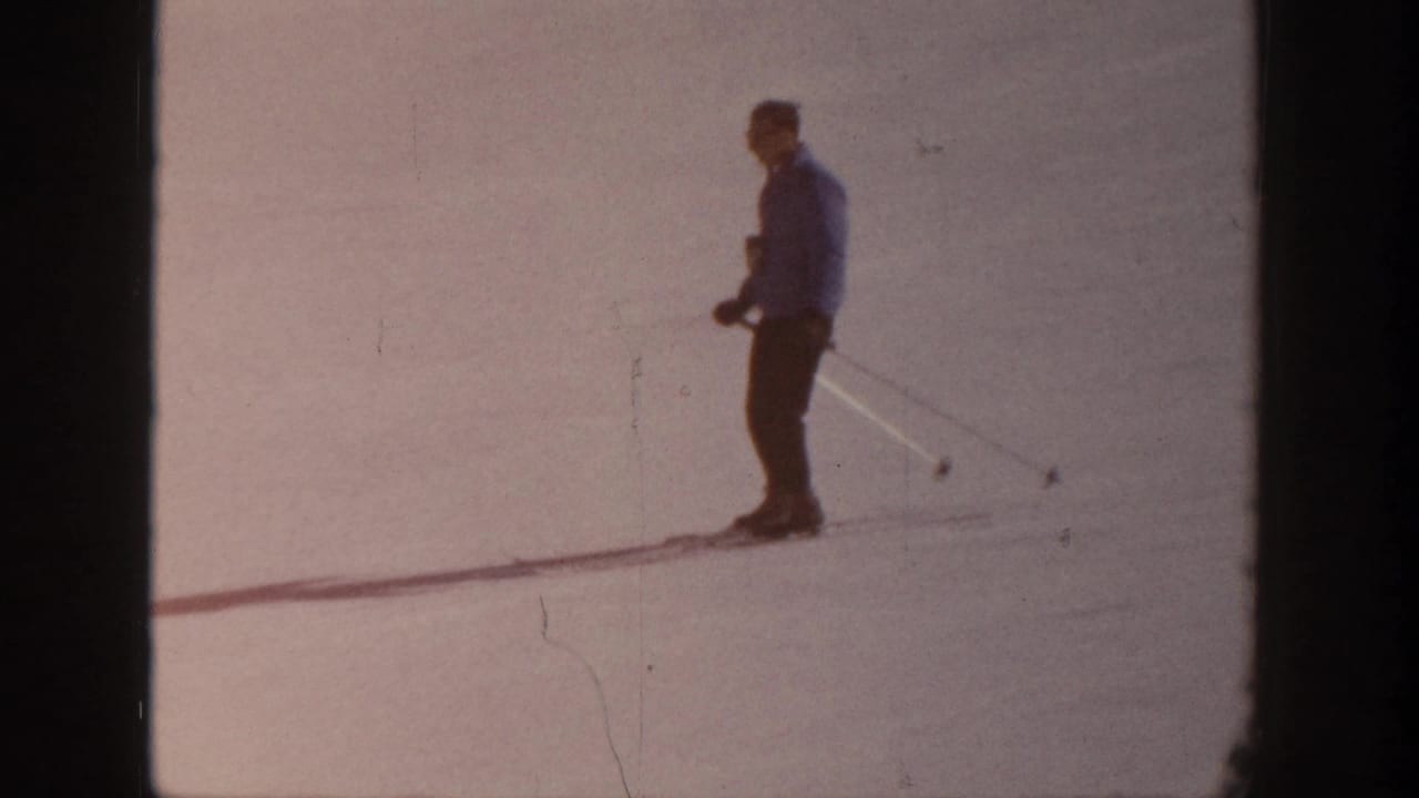 A lone skier in winter clothing stands on a snowy Aspen slope in 1961-era 8mm home-movie footage.