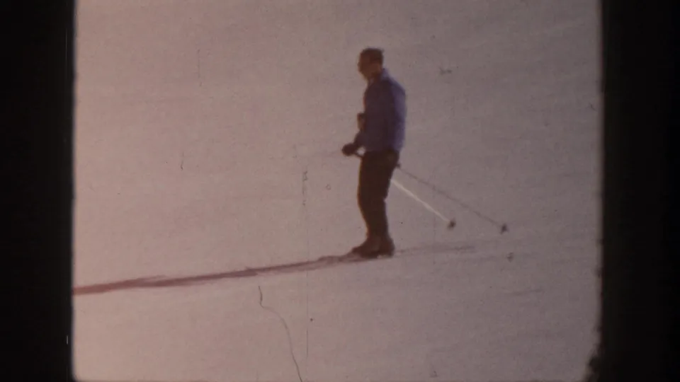 A lone skier in winter clothing stands on a snowy Aspen slope in 1961-era 8mm home-movie footage.