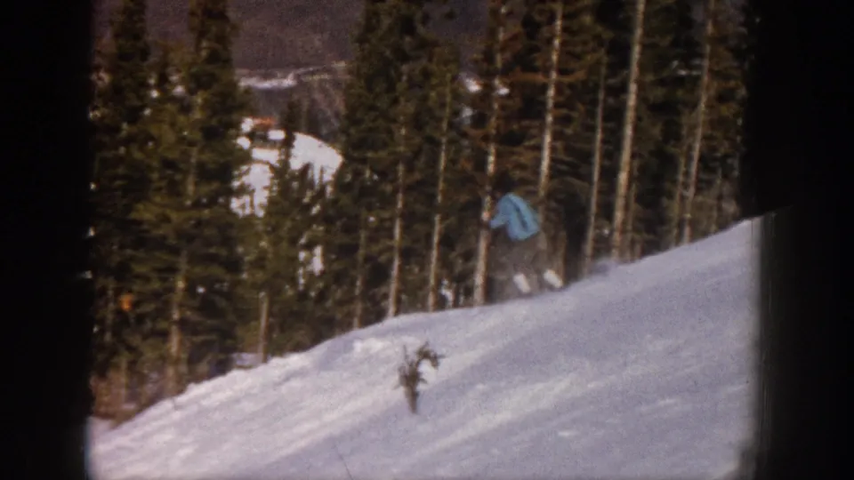 1961 Aspen 8mm frame showing the skier partly obscured near the right edge while descending a bumpy snow-covered hill.