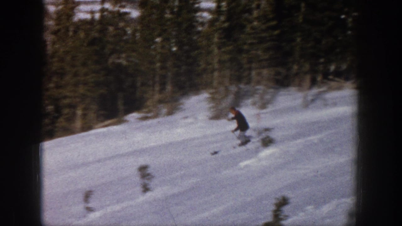 A distant skier in dark winter clothing moves down a snowy Aspen, Colorado slope in 1961 home-movie footage.