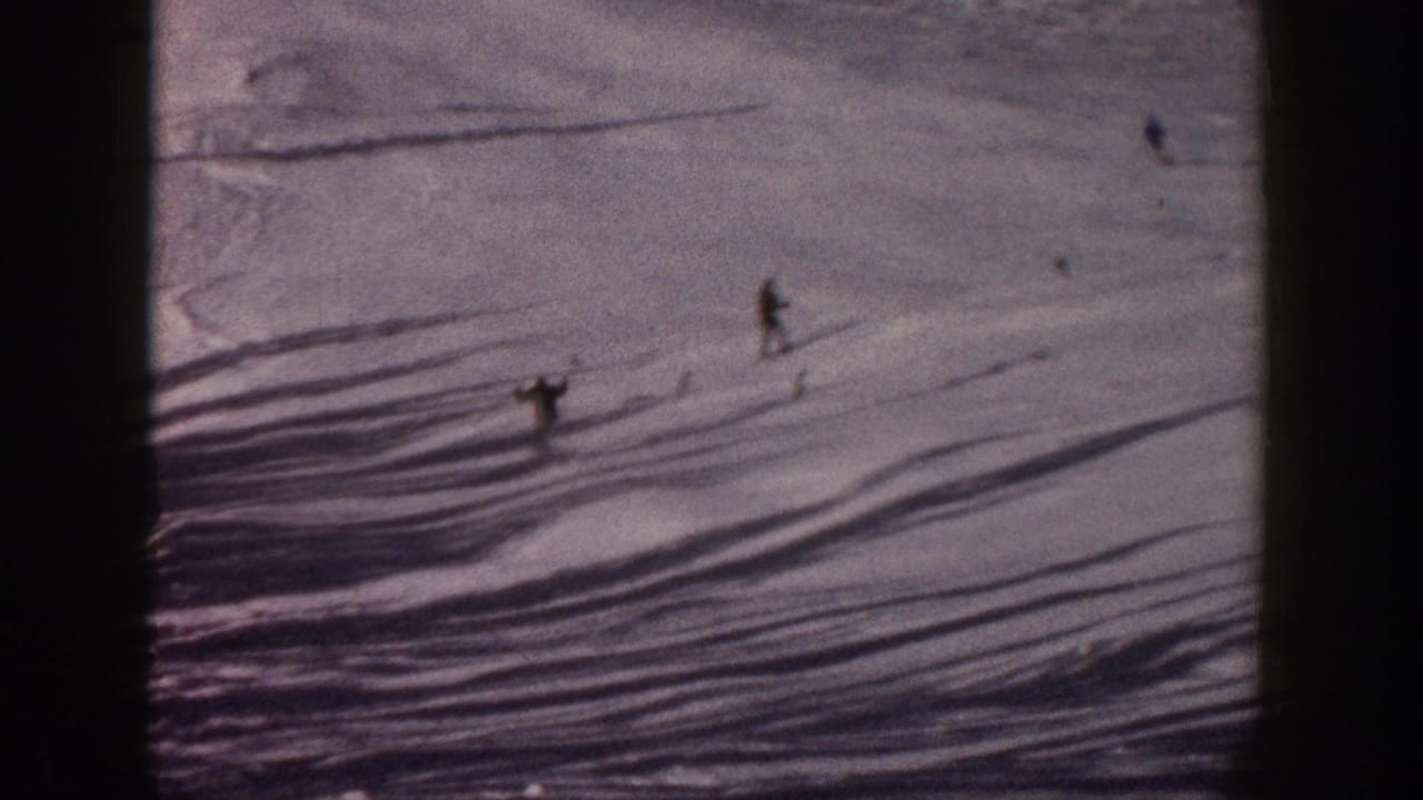 1961 Aspen 8mm frame showing distant skiers on a snow-covered slope with elongated shadows and soft color grain.