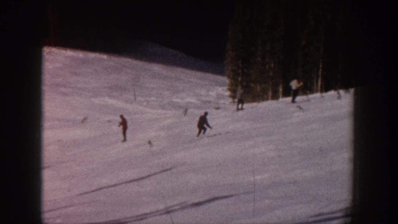 Distant skiers traverse an Aspen, Colorado snow slope in faded 8mm home-movie footage from 1961.