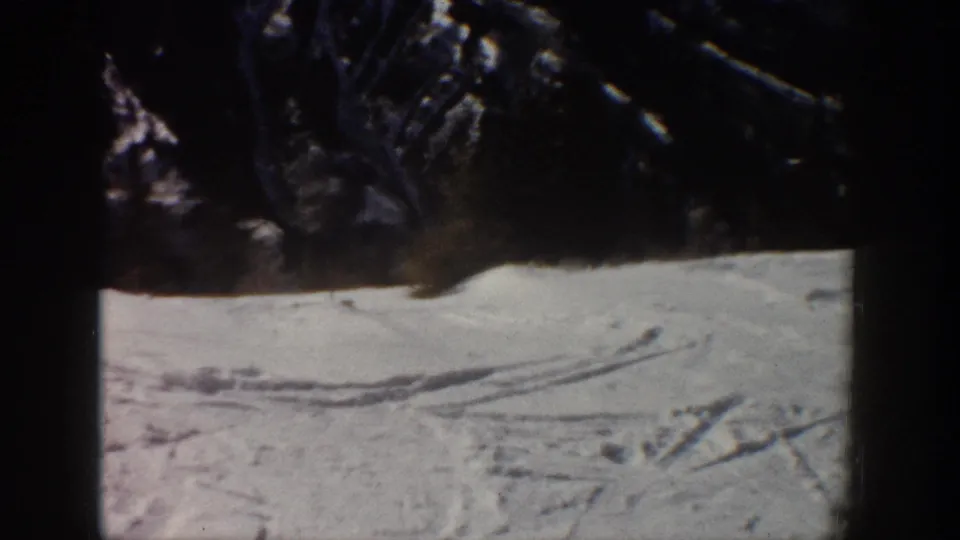 End frame from the Aspen ski clip showing snow tracks across a bright slope under dark mountain ridges and 8mm frame edges.
