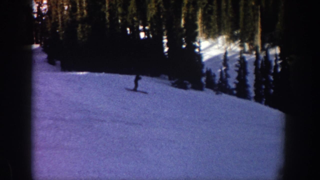 1961 Aspen, Colorado ski footage with a lone skier moving down a wooded snow slope.