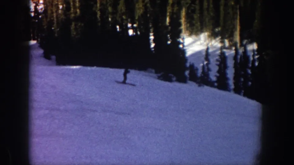 1961 Aspen, Colorado ski footage with a lone skier moving down a wooded snow slope.
