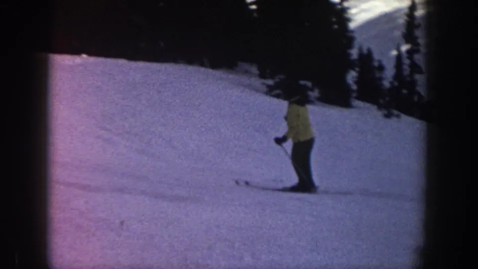1961 Aspen frame showing a skier on a broad snowy slope, with evergreen trees and heavy 8mm color shift.