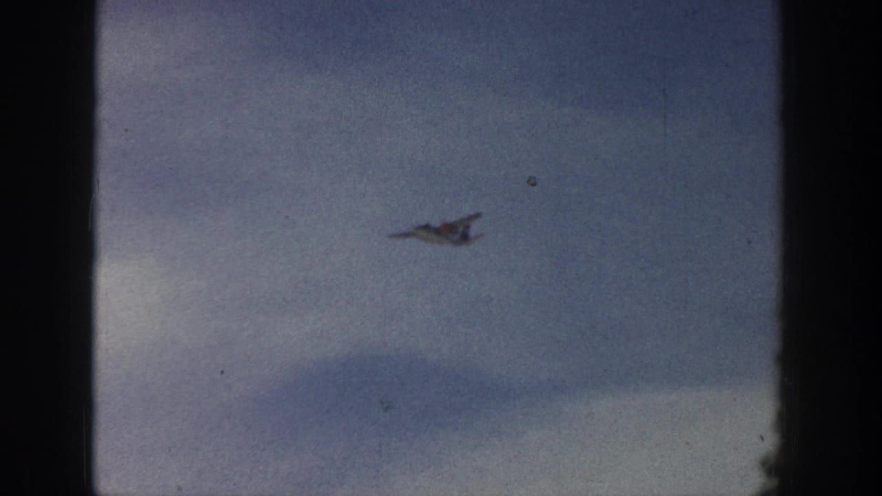 Small airplane seen at a distance against a cloudy blue sky.
