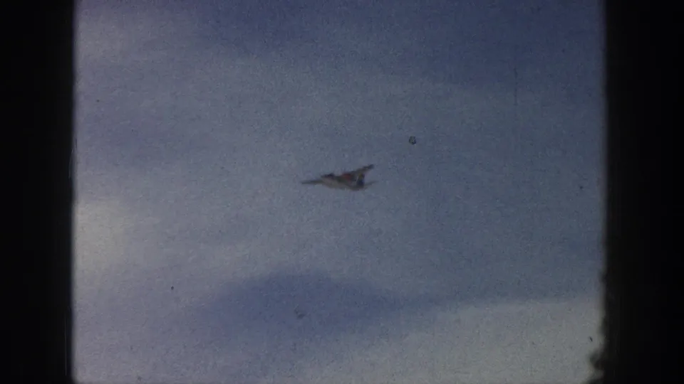 Small propeller airplane flying through a cloudy sky in a 1961 Aspen travel home-movie sequence.