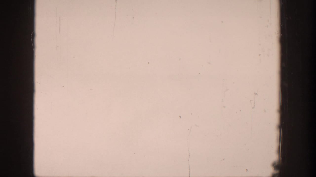 Pale Aspen sky and thin cloud haze on 1961 8mm film, with the aircraft no longer clearly visible in this frame.