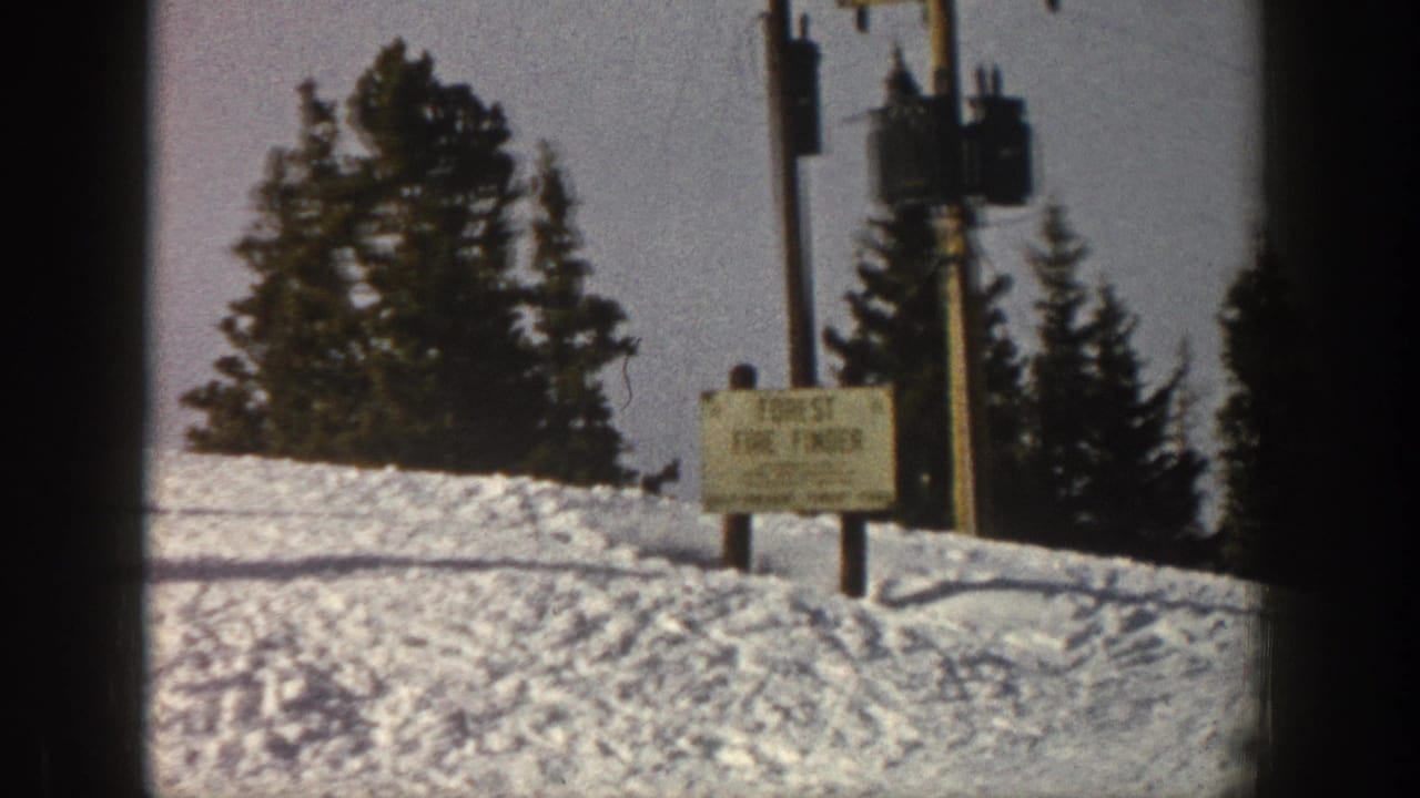 Aspen, Colorado 1961 8mm frame showing a snow-covered slope, evergreens, pole equipment, and a forest fire finder sign.