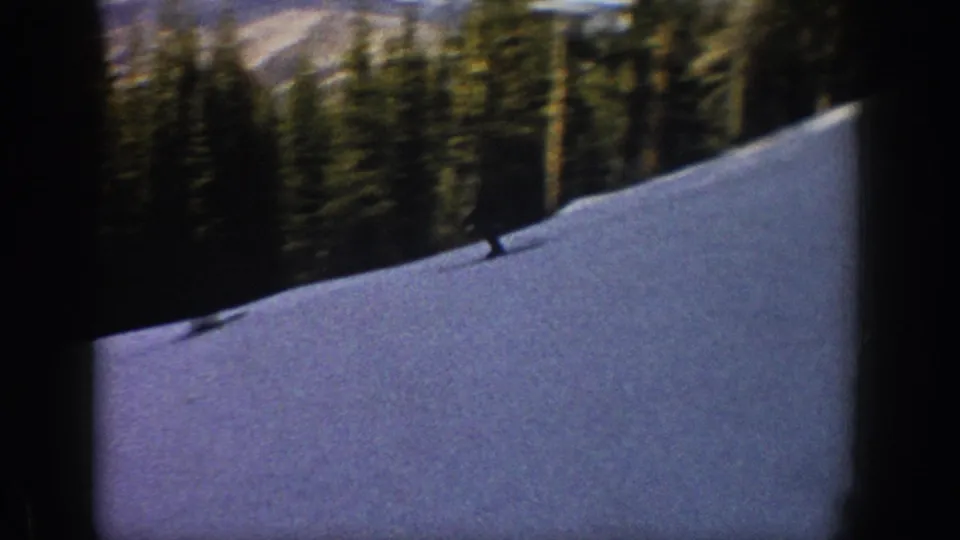 Aspen, Colorado 1961 8mm frame showing a skier descending through shadow on a snow slope beneath evergreens.