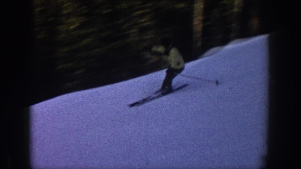 A skier in a light jacket and dark pants moves downhill on a snowy Aspen slope in 1961 home-movie footage.