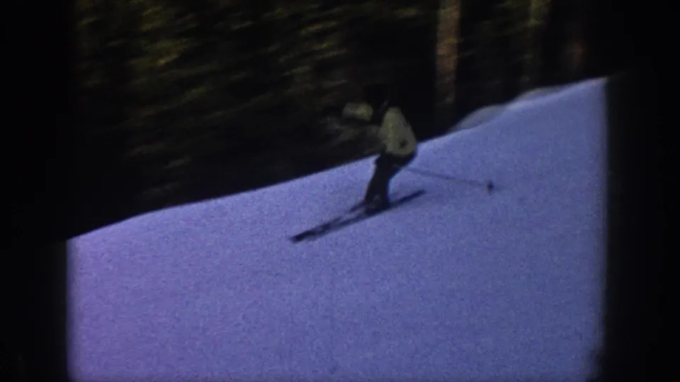 A skier in a light jacket and dark pants moves downhill on a snowy Aspen slope in 1961 home-movie footage.