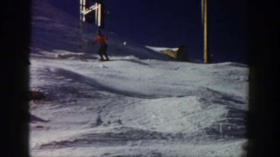 Aspen, Colorado 1961 frame of a skier in red descending a snow-covered slope with a ski lift structure visible above.