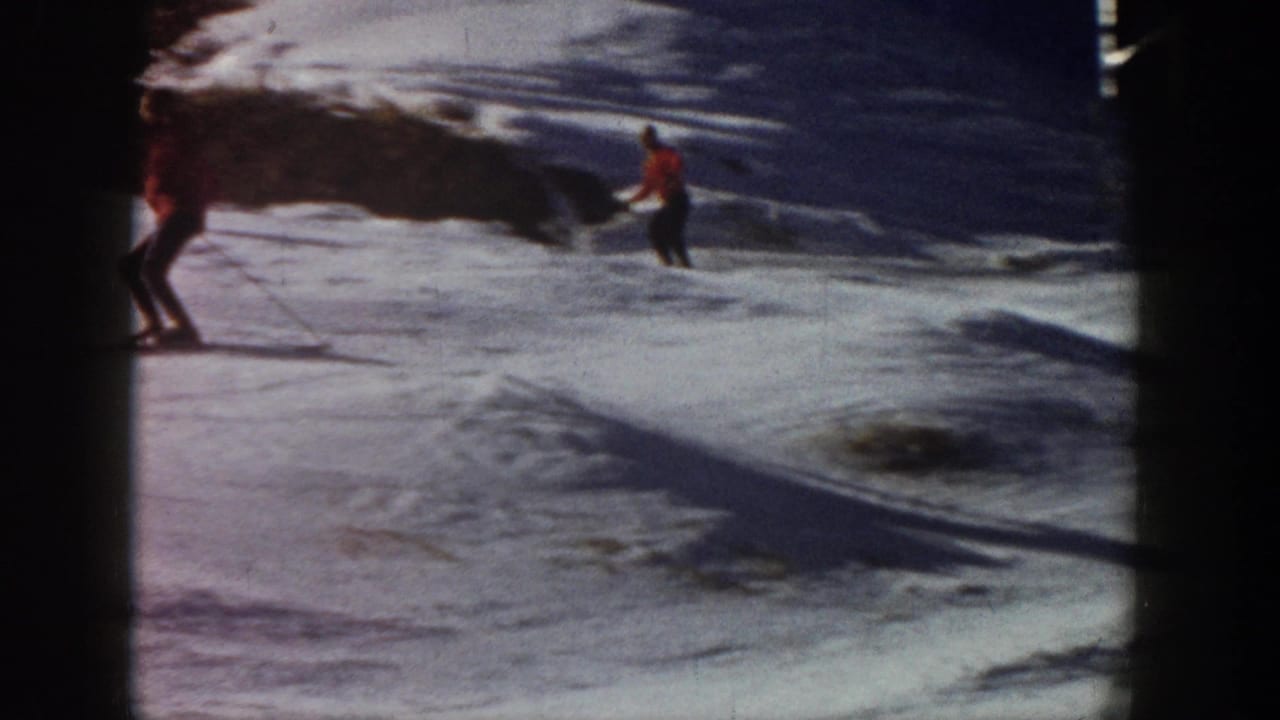 Aspen, Colorado 1961 home-movie frame with one skier entering at left and another in red crossing a snowy slope near exposed ground.