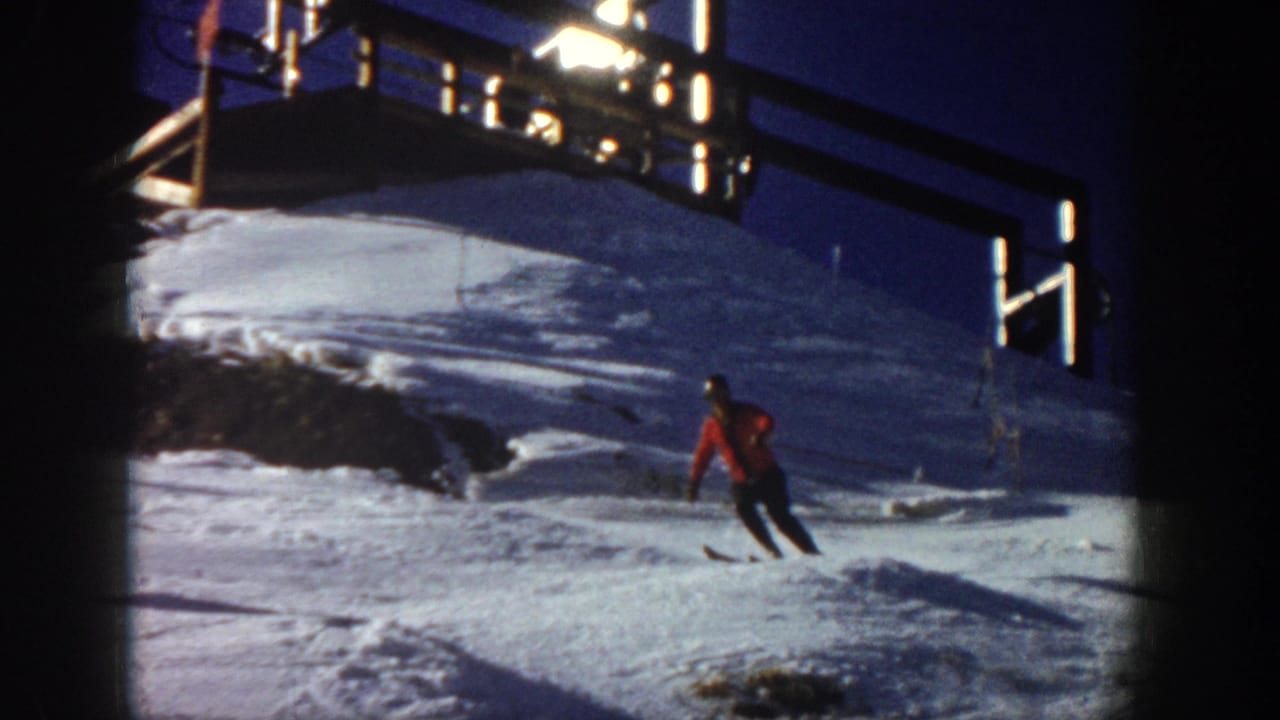 1961 Aspen frame showing a red-jacketed skier turning across the snow below a raised lodge or lift-area structure.