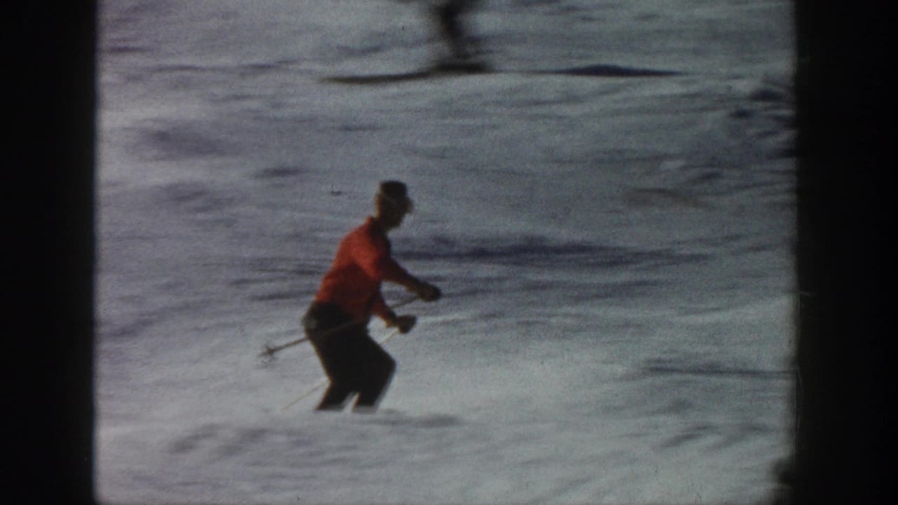 Near the end of the Aspen clip, the skier passes lower in frame, partly softened by motion blur against the snowy run.