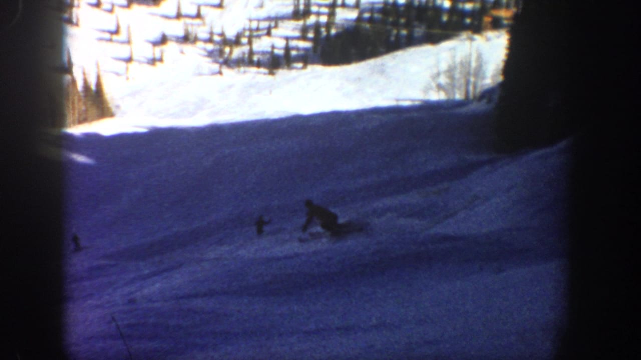 Near the end of the clip, the distant skier is low against the shaded Aspen snow, with trees and bright slope above.