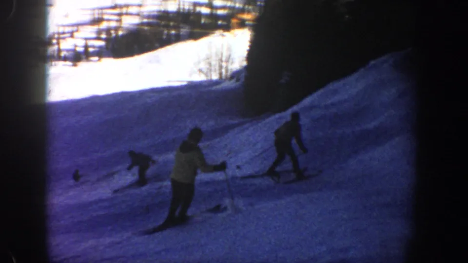 1961 Aspen frame showing multiple skiers on a snowy slope with trees and bright snow in the background.