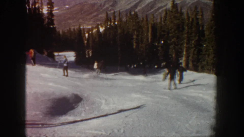 1961 Aspen-area ski footage with one skier turning near the foreground and several others farther up the tree-lined slope.