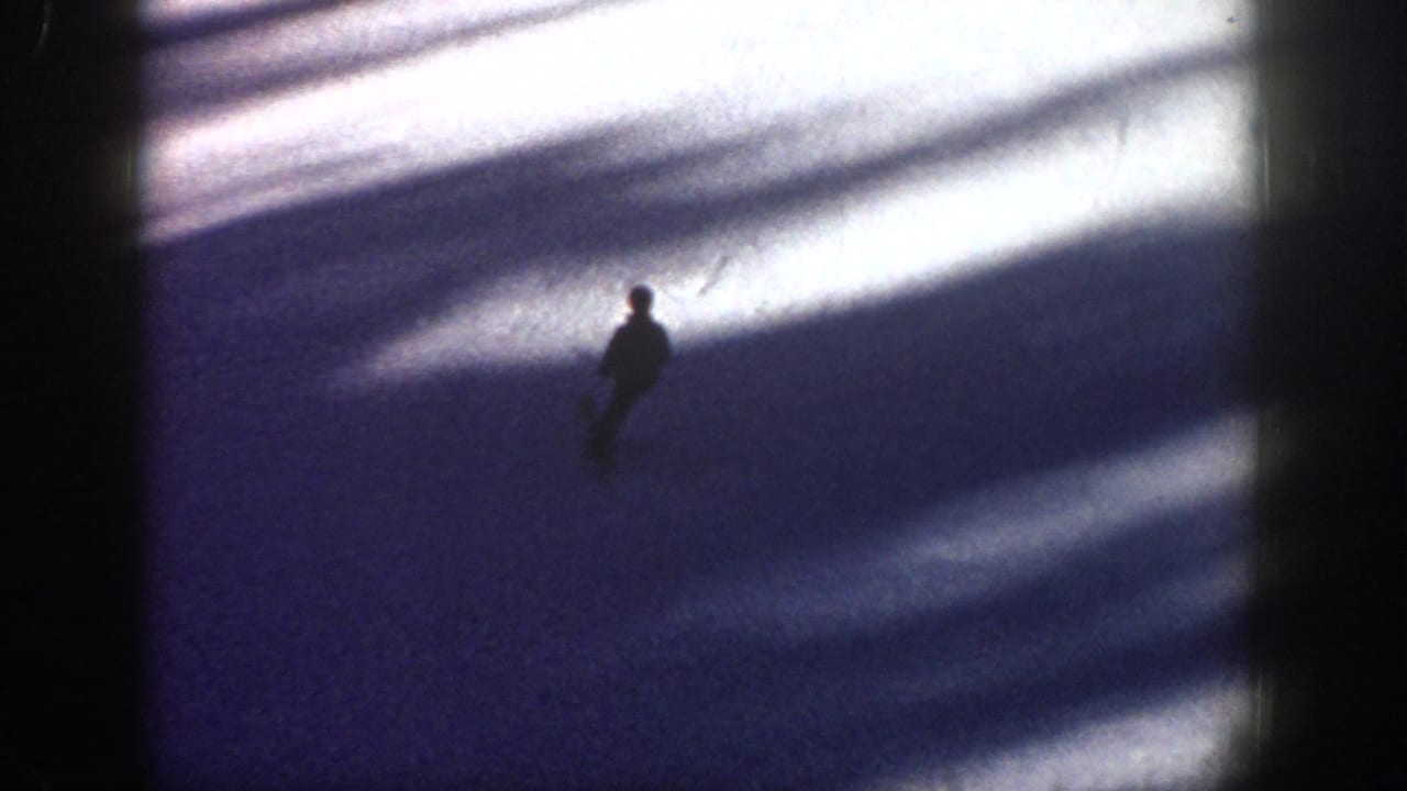 Small skier figure on a blue-shadowed snowy slope.