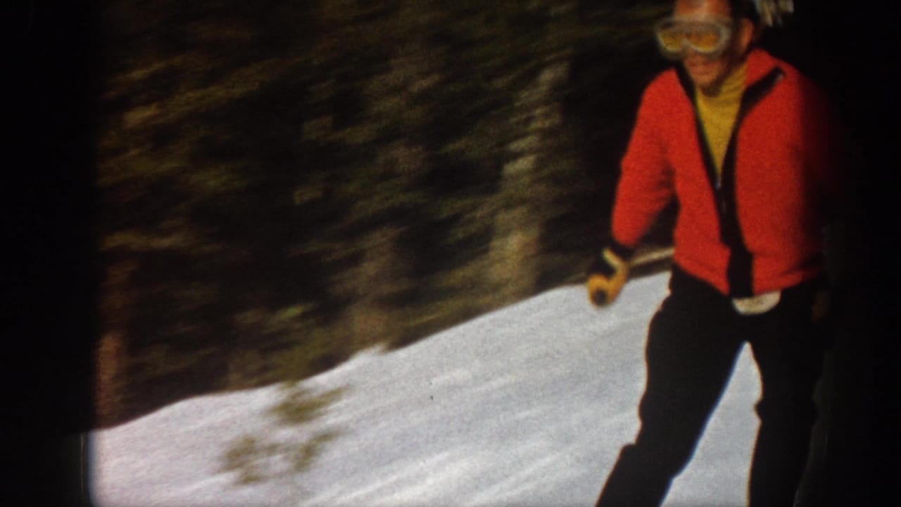 Red-sweater skier passes close to the camera on a snowy slope.