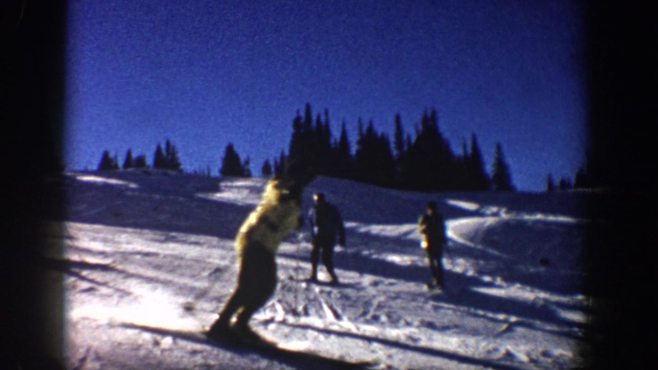 1961 Aspen skiing frame with a skier turning in the foreground, distant figures, tree line, and saturated 8mm color.