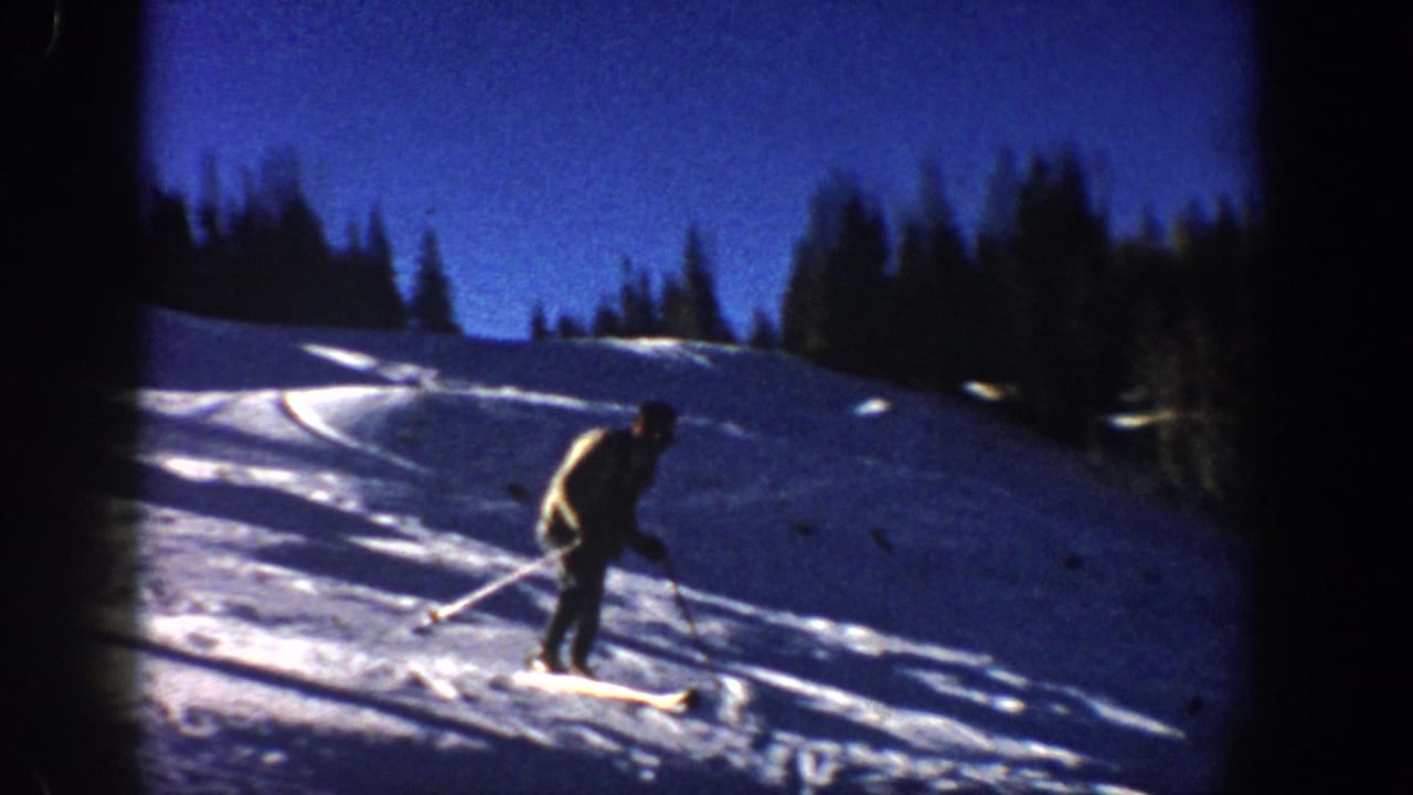 1961 Aspen winter frame showing a skier in profile crossing a bright slope with ski tracks and evergreens behind.