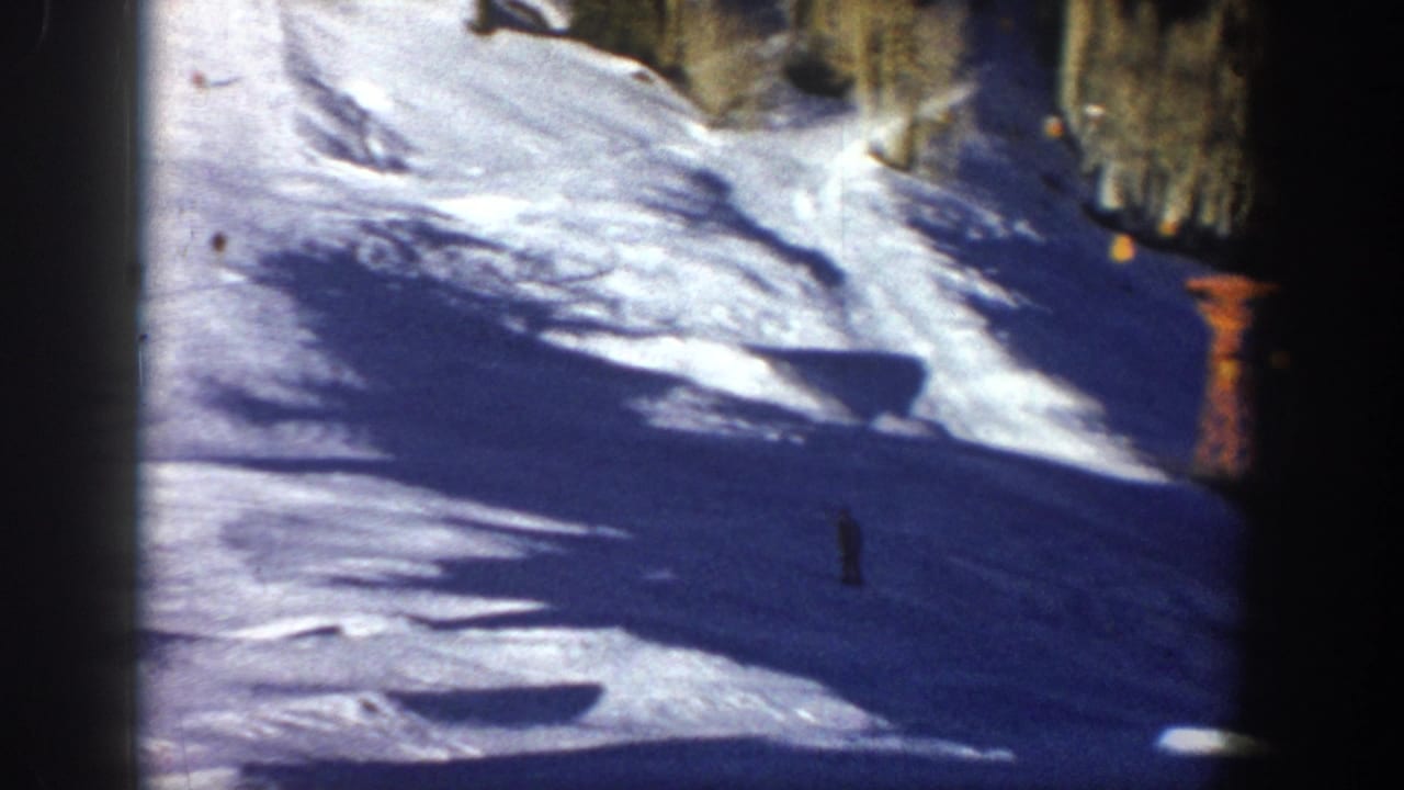1961 Aspen home-movie frame showing a sunlit snowy slope with distant skiers and aspen trees near the run.