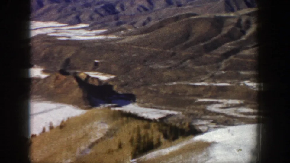 1961 Aspen-area 8mm frame showing a snow-patched valley, brown ridges, and distant mountain terrain.