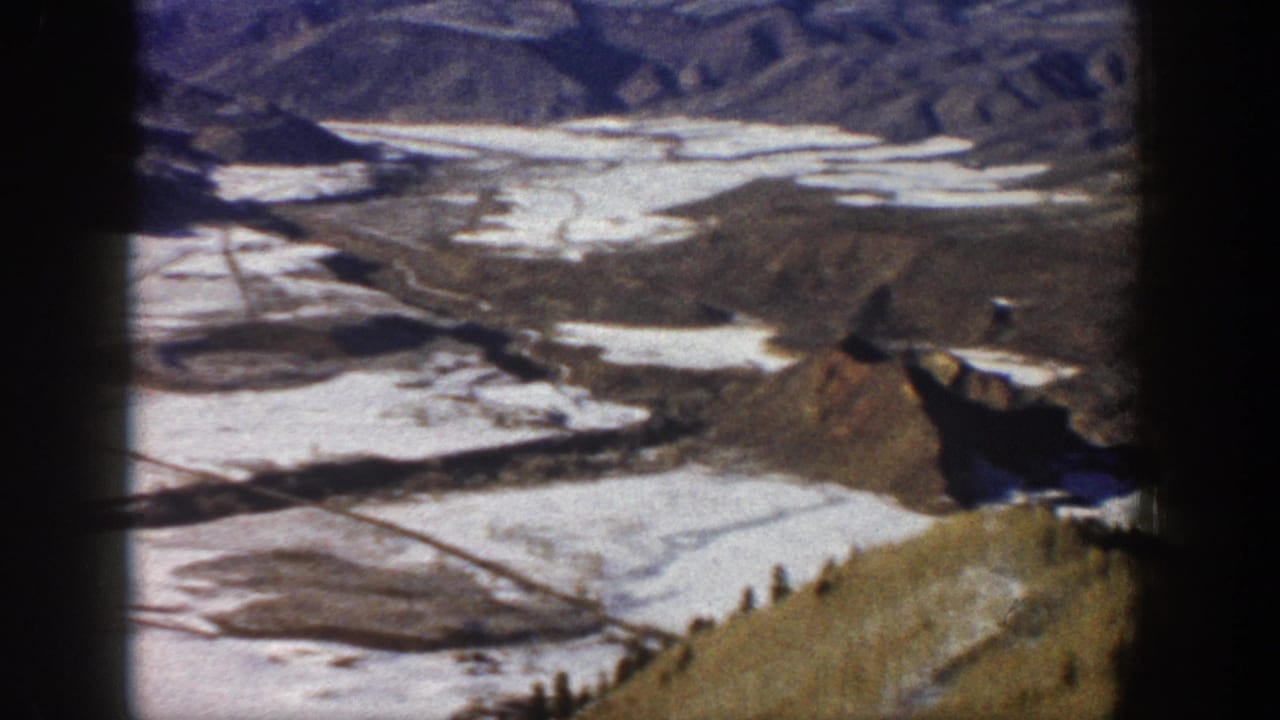Wide view of snow-covered valley and rugged brown hills.