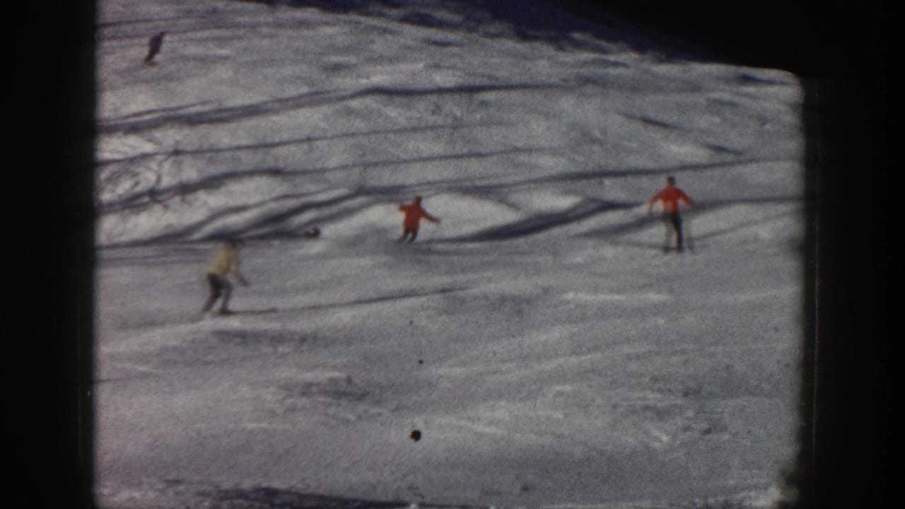 1961 Aspen, Colorado home-movie frame showing distant skiers in colored coats moving down a bright snowy slope.