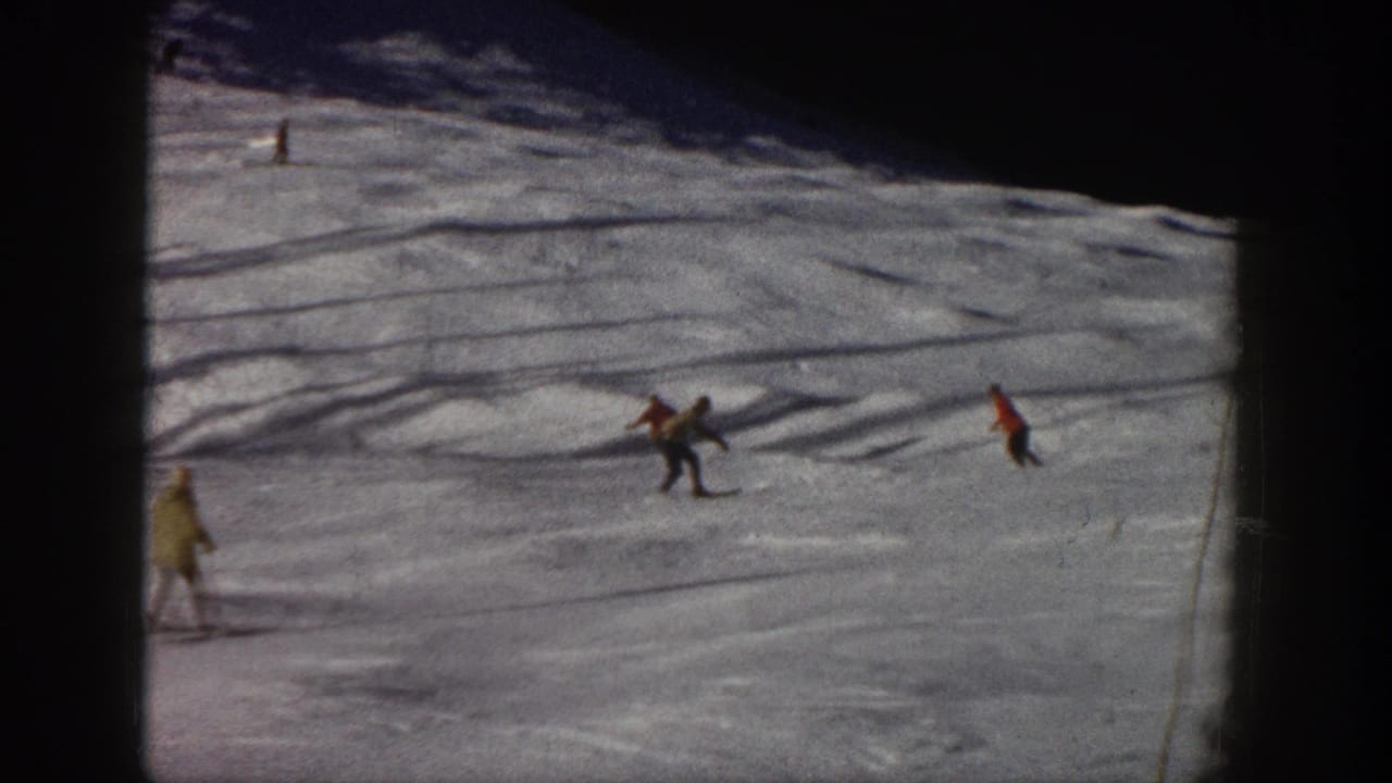 Skiers move across a wide snowfield, including one pair near the center.