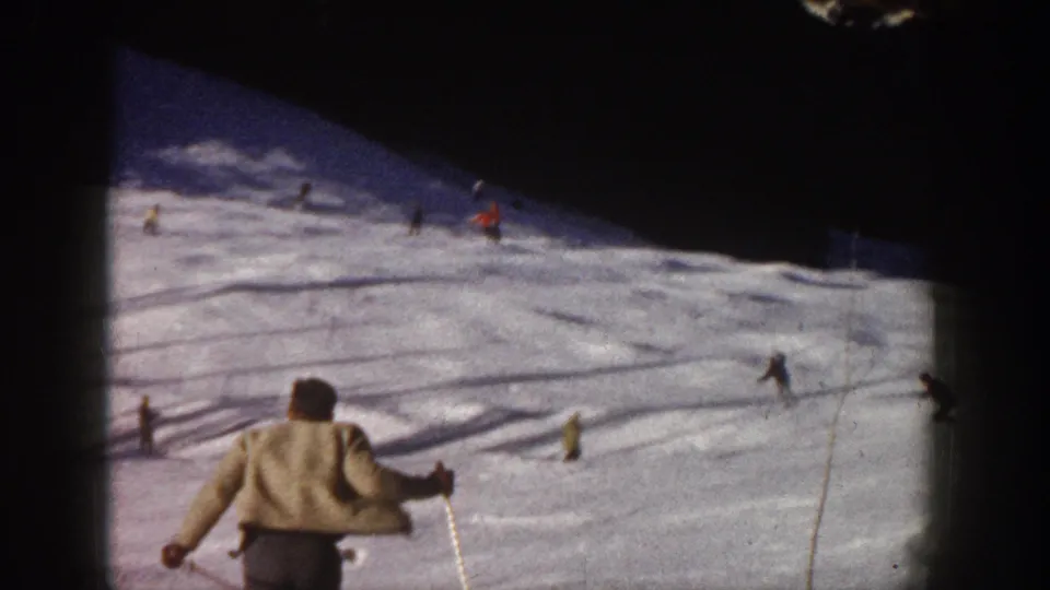 1961 Aspen ski footage with a light-jacketed skier in the foreground and other skiers scattered across the run.