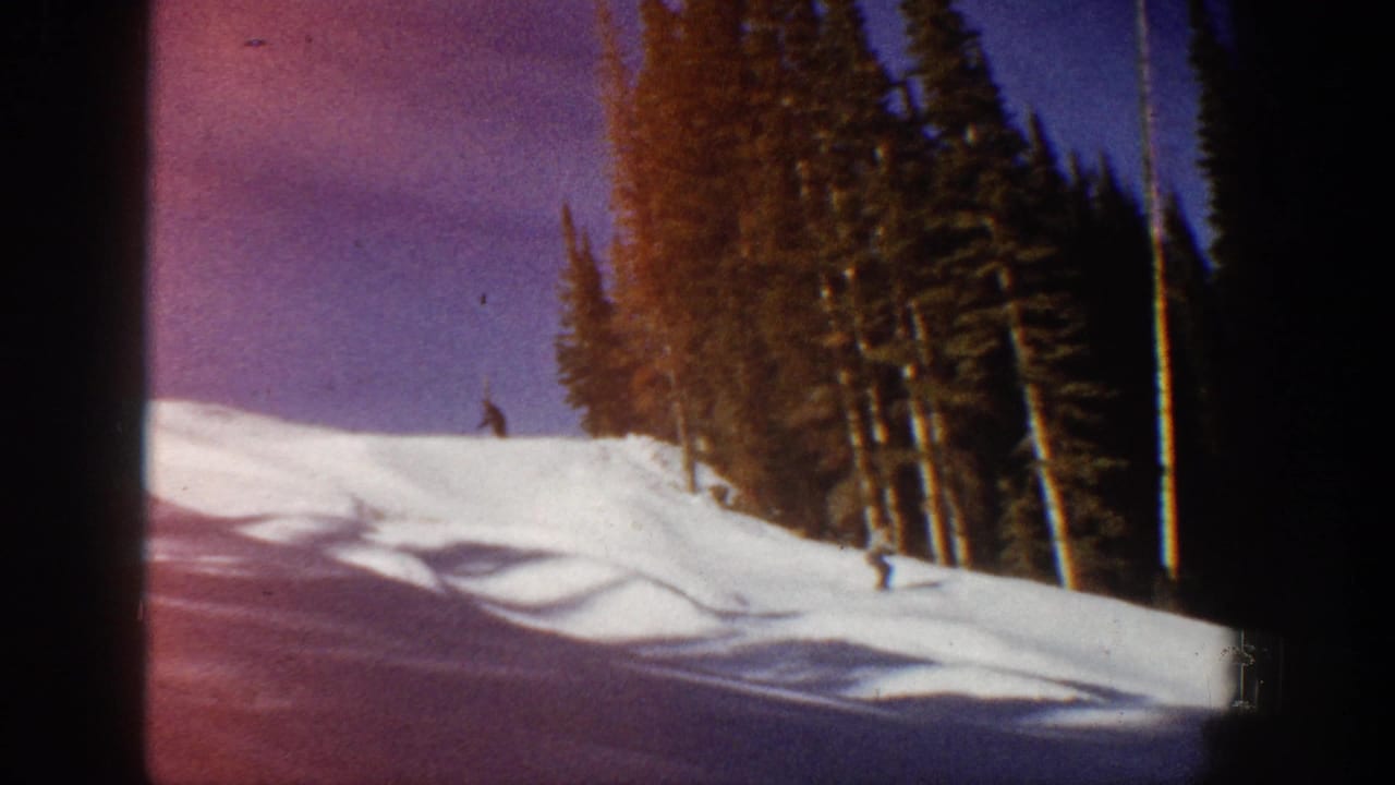 Aspen 8mm frame showing a distant skier on a snowy slope with pine trees, strong shadows, and magenta color shift.
