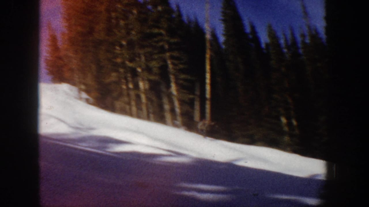Aspen, Colorado 1961 home-movie frame showing a snowy ski slope beside dense evergreens, with no skier clearly visible.