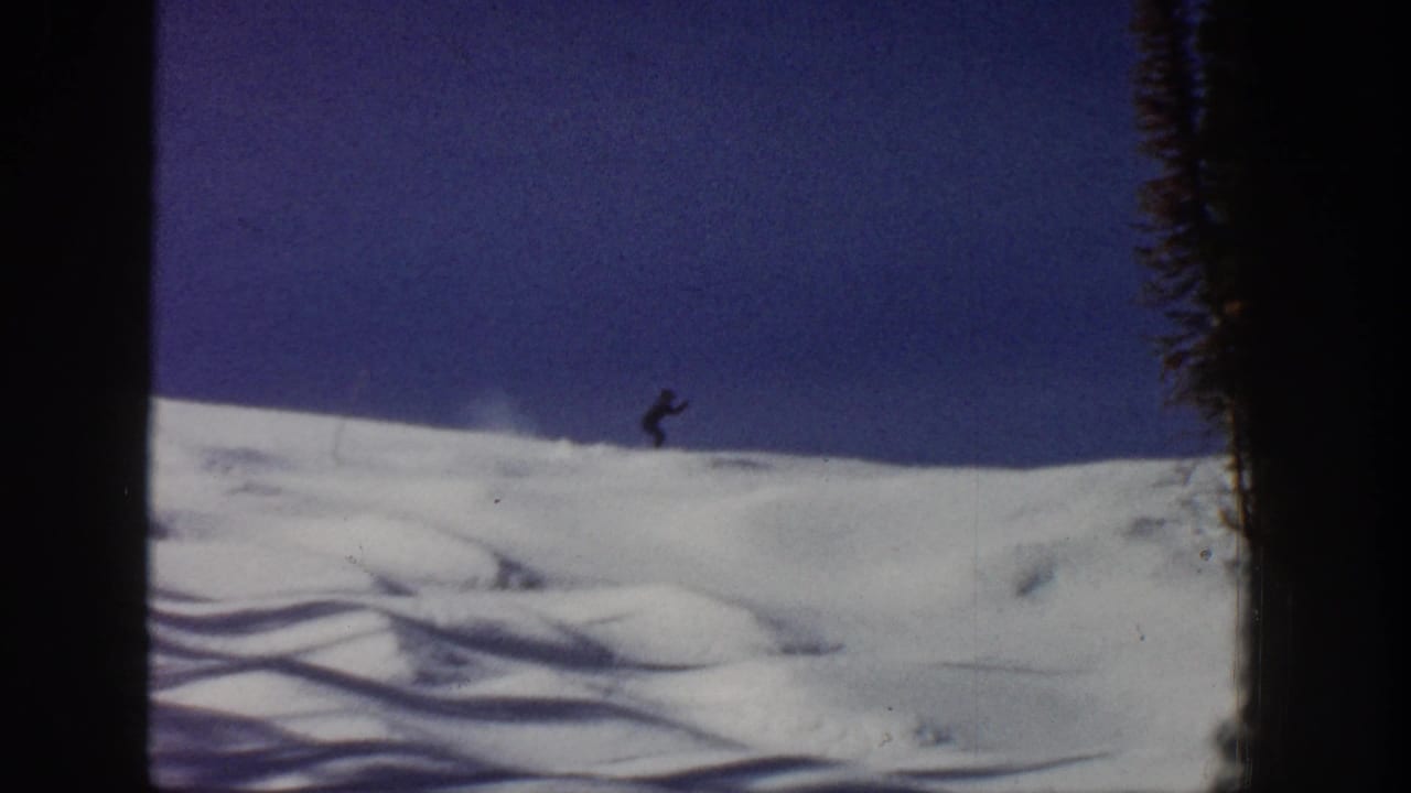 1961 Aspen 8mm frame showing a distant skier crossing a snowy slope beneath a deep blue sky.